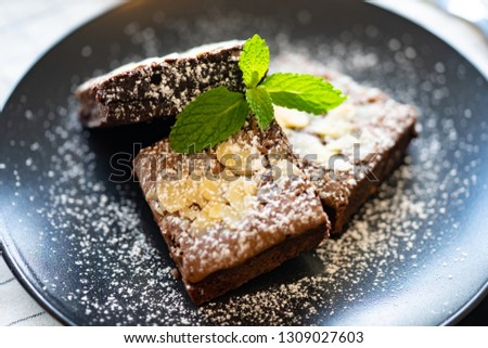 Brownie stack with almonds.A stack of chocolate brownies on wooden background with mint leaf on top, homemade bakery and dessert concept.