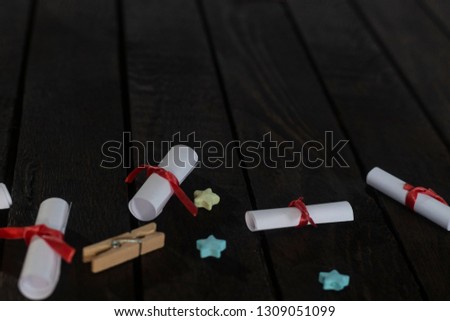 Flat lay romantic background. Top view to giftbox, rolled wish papers, and wooden frame with paper hearts on dark wood board.