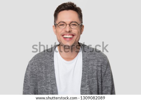 Funny happy millennial man wearing glasses laughing looking at camera, young guy chuckling smiling isolated on white grey studio blank background, male student nerd giggling having fun, portrait