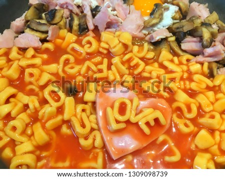 Alphabet shape pasta in tomato sauce written with word Love on heart shaped ham also with mushrooms and cooked egg