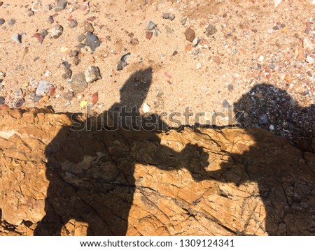 The shadow of the woman and the man hand in hand walking to the beach.