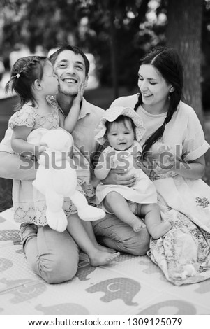 Portrait of happy family. Smiling parents with their child. Handsome father and beautiful mother with little cute daughter having fun in the park. Pretty kid kisses her daddy, pretty woman