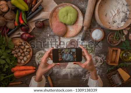 Food blogger concept. Young woman recording video on smartphone at kitchen. Woman recording every step of cooking process for her blog. Diet, technology, health, food, cooking, culinary, and people.