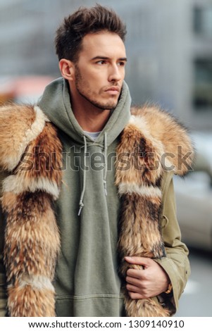 Fashionable man walk outdoors wear  fur jacket with street background - Image
