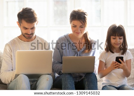 Family with kid using laptops and smartphone at home, parents and little child daughter addicted to social media on devices, gadgets dependence overuse, people internet technology addiction concept