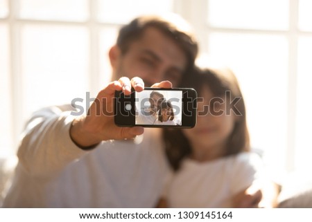 Father holding phone taking selfie with kid daughter on modern smartphone camera, happy family dad and child making photo on gadget at home, focus on device with self portrait image on mobile screen