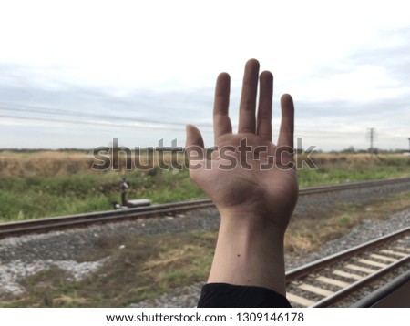 Abstract picture of one single opened hand with background of the Railroad and full of many trees