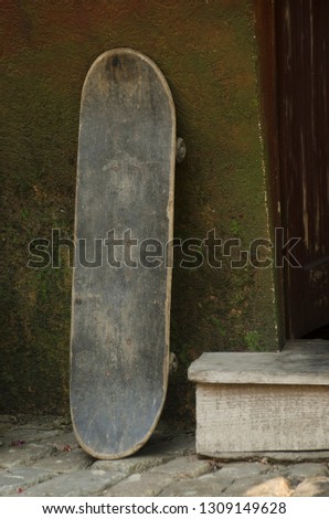 Old skateboard leaning against a wall