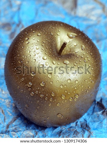 golden apple with dew drops on a blue background. close up