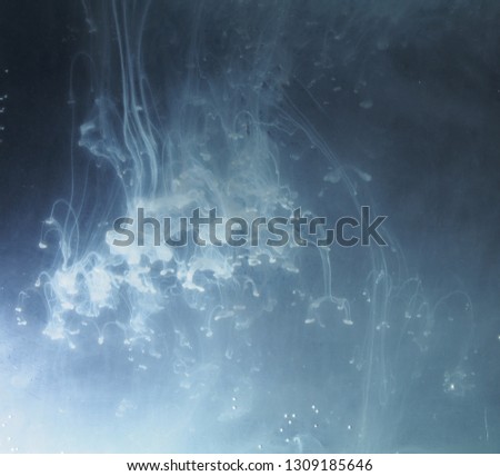 A drop of paint dissolves in water. On black background. Abstract figures.