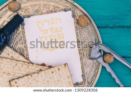 Metal plate with matzah or matza and Passover Haggadah on a vintage wood background presented as a Passover seder feast or meal. Translation: Passover Haggadah

 Royalty-Free Stock Photo #1309228306