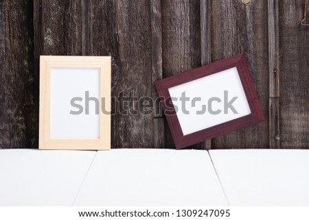 brown painted and natural wood picture frame, white table, old wooden wall