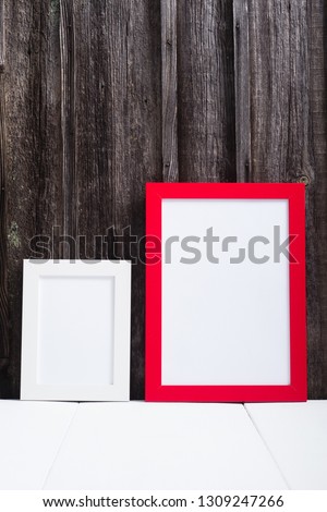 white and red blank picture frames, white table, old wooden wall
