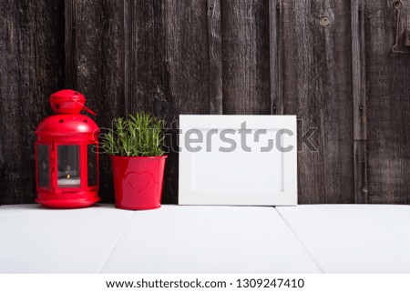 white picture frame,red lantern,lavender in enamel pot, white table, old wooden wall