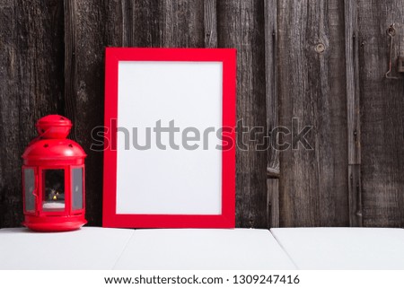 red picture frame, lantern, white table, weathered wooden wall