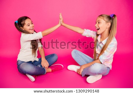 Close up side profile photo two little age she her girls hands arms clap best friends sit floor legs crossed wearing casual jeans denim checkered plaid shirts isolated rose vibrant vivid background