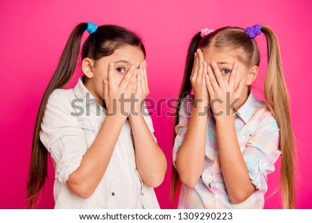 Close up photo two little age girls hands arms hide head palms show one eye full of fear wearing casual jeans denim checkered plaid shirts isolated rose vivid bright background