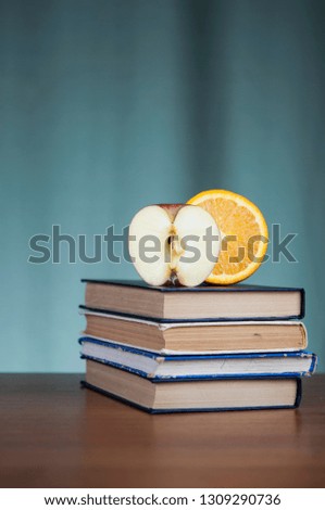 Stack of books and red apple on wooden table 