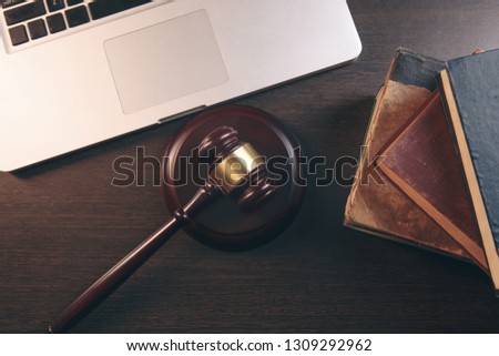 Gavel with books and scales on brown background