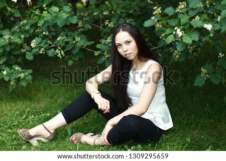 Portrait of the beautiful young girl in the summer city garden.