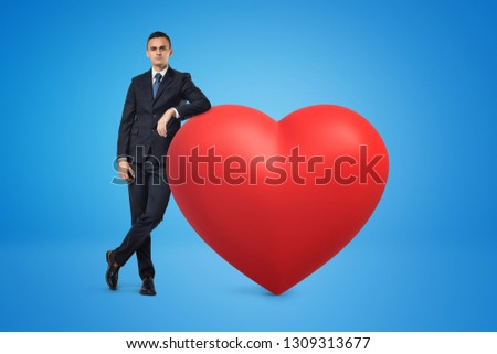 Businessman and big red heart model on blue background. Feelings and emotions. People and objects. Signs and symbols.