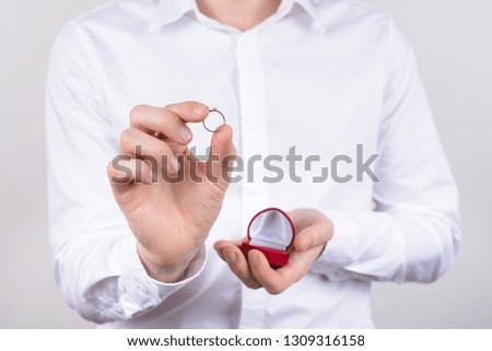 Closeup photo cropped picture of happy cheerful excited glad positive optimistic guy holding small little ring in hand with fingers isolated grey background