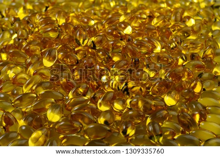 Pile of gold colored softgel Vitamin capsules reflecting light Royalty-Free Stock Photo #1309335760