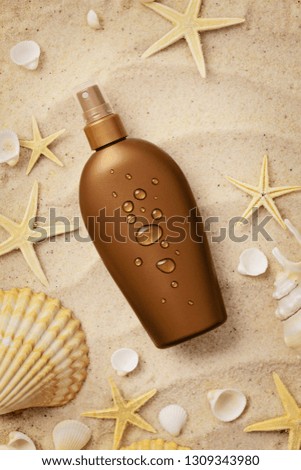 suntan cream bottle and seashells on sand beach