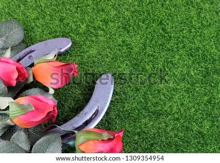 Red silk roses, a horseshoe and artificial green grass for the running of the thoroughbred race called the Kentucky Derby. Copy space Royalty-Free Stock Photo #1309354954