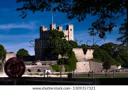 castle at the top of a hill with a river 