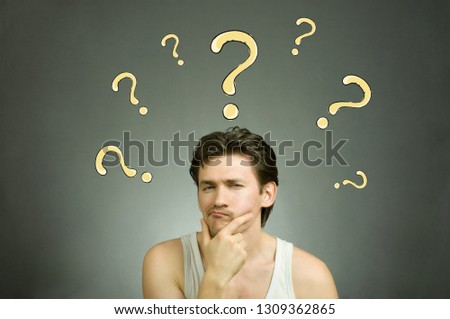 Man thinks and question marks overhead. Stock photo.