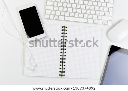 Top View of trendy White Office Desk with keyboard, white earphones and office supplies