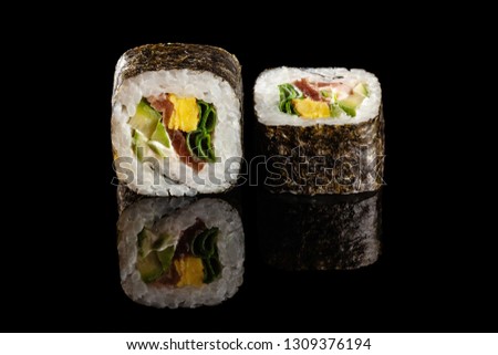 Concept of Asian cuisine. Two rolls of sushi with different fillings on a black background with the age for a Japanese menu for a cafe, restaurant, sushi bar.