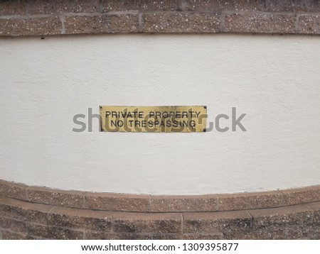 gold or brass private property no trespassing sign on wall with bricks