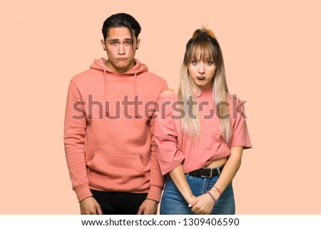 Young couple with sad and depressed expression over pink background