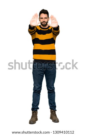 Full-length shot of Handsome man with striped sweater making stop gesture for disappointed with an opinion on isolated white background