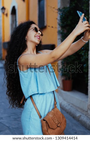 Happy teenage girl on European summer vacations video-calling using smartphone