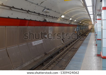 Underground subway station with approaching train in distance in large urban area