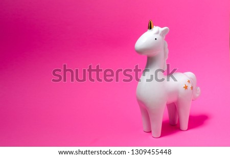 White porcelain unicorn figurine on pink pastel background. White unicorn. Home decoration.  Unicorn photos. Closeup unicorn figure.