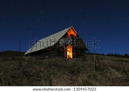 Cabin with fire, montain night and stars  Royalty-Free Stock Photo #1309457023