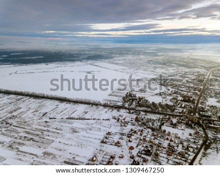 Top view of empty snowy fields on winter morning on dramatic cloudy sky background. Aerial drone photography concept.