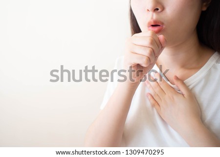 Young ill female have a cough and sore throat over white background. Causes of cough include pneumonia, bronchitis, allergy, asthma, COPD, TB or respiratory tract infection. Copy space. Health care. Royalty-Free Stock Photo #1309470295