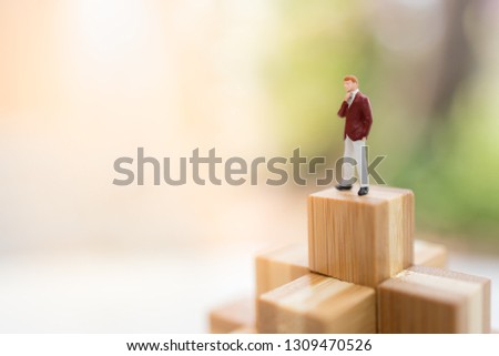 Miniature people: Businessman standing on wood block step with copy space for text using as background money, finance, business concept.