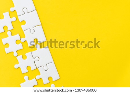 White jigsaw puzzle on vivid yellow background with copy space using for thinking strategy for business solution, teamwork, connection or idea for success.