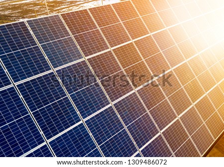 Close-up surface of lit by sun blue shiny solar photo voltaic panels. System producing renewable clean energy. Renewable ecological green energy production concept. Royalty-Free Stock Photo #1309486072