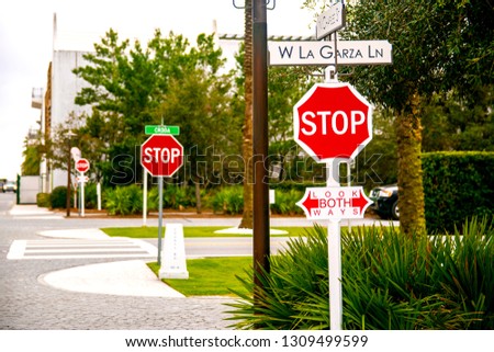 Three Stop Signs At Crosswalk Intersection In Alys Beach Florida With Plants and Palm Trees In Background