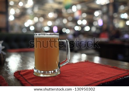 Glass of light beer in a dark pub