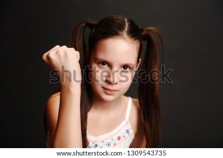 little girl shows fist on black background
