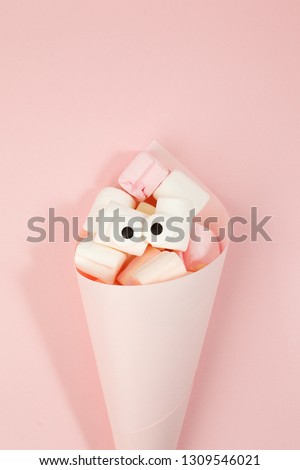 Marshmallows with eyes in paper cone. Funny kawaii emoji face. Cute cartoon character. Minimal summer flat lay design. Sweet food. Pink background, monochrome concept