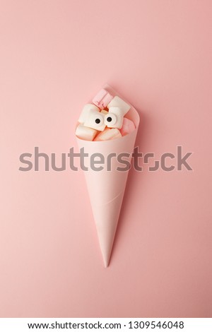 Marshmallows with eyes in paper cone. Funny kawaii emoji face. Cute cartoon character. Minimal summer flat lay design. Sweet food. Pink background, monochrome concept